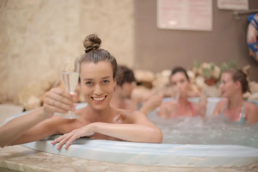 Friends raising a glass in a bubbling hot tub