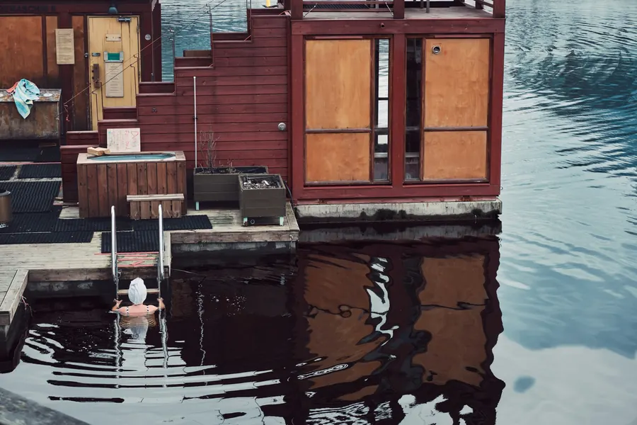 A plunge pool on a lakeside deck beside a floating sauna